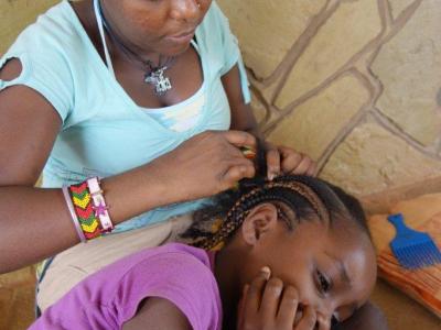 Mwanajuma flechtet einem anderen Kind die Haare